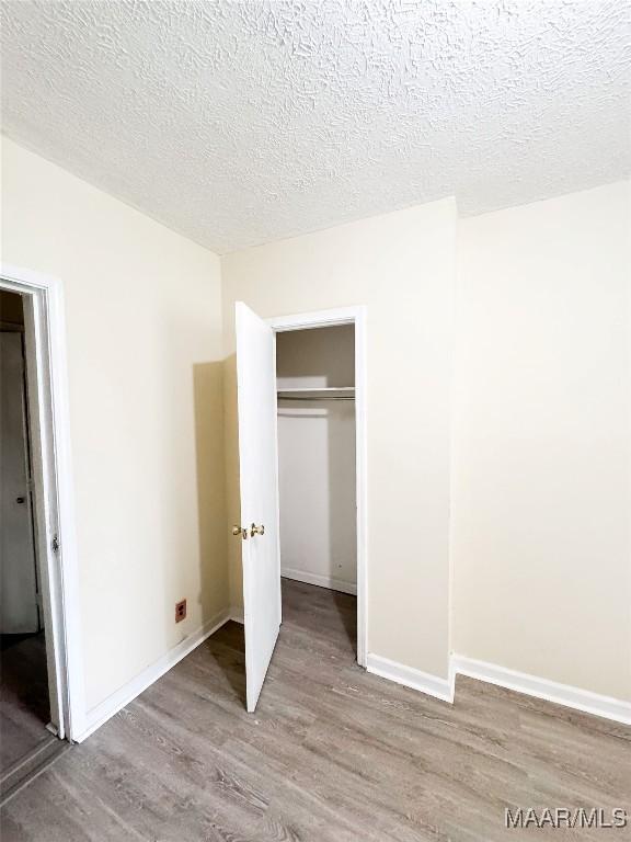 1422 S Holt St, Montgomery, AL 36108 - unfurnished bedroom featuring light wood-type flooring, a textured ceiling, a closet, and baseboards