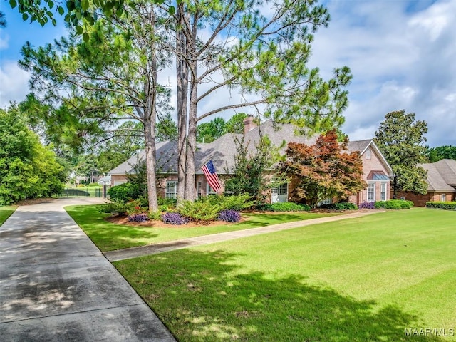 8054 Lakeridge Dr, Montgomery, AL 36117 - view of property hidden behind natural elements with driveway, a front lawn, and a chimney