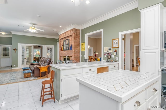 8054 Lakeridge Dr, Montgomery, AL 36117 - kitchen featuring tile counters, a ceiling fan, a fireplace, a sink, and open floor plan