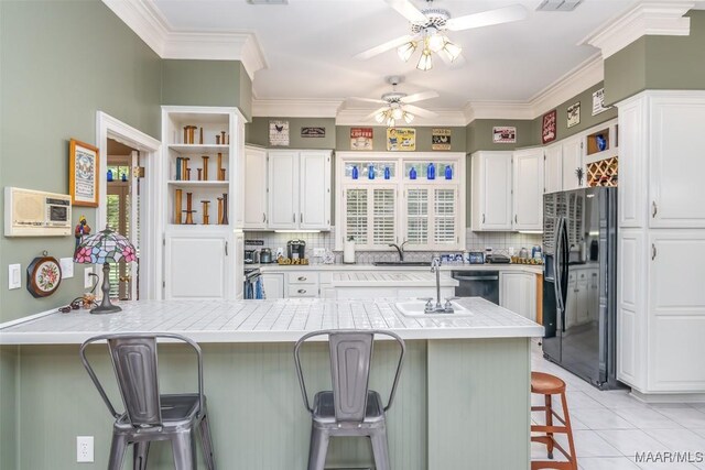 8054 Lakeridge Dr, Montgomery, AL 36117 - kitchen with black refrigerator with ice dispenser, ceiling fan, tasteful backsplash, white cabinets, and crown molding