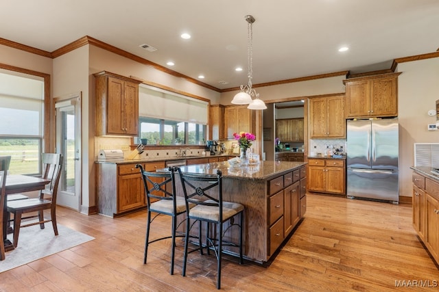 511 Mehearg Rd, Wetumpka, AL 36092 - kitchen featuring appliances with stainless steel finishes, crown molding, a kitchen island, brown cabinetry, and recessed lighting
