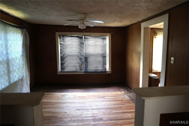 2612 Harris St, Selma, AL 36701 - unfurnished dining area with a ceiling fan, a textured ceiling, wood finished floors, wood walls, and healthy amount of natural light