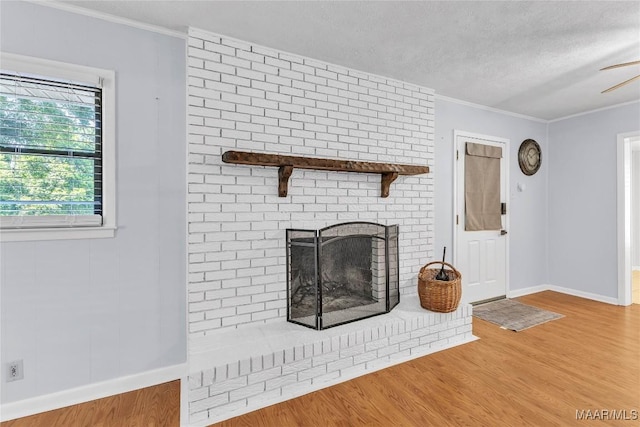 211 Murfee Dr, Prattville, AL 36066 - unfurnished living room featuring wood finished floors, a textured ceiling, a brick fireplace, crown molding, and a ceiling fan
