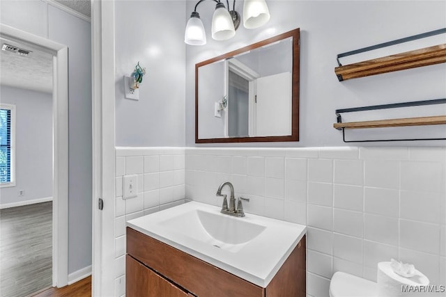 211 Murfee Dr, Prattville, AL 36066 - half bathroom featuring vanity, tile walls, wood finished floors, toilet, and a textured ceiling