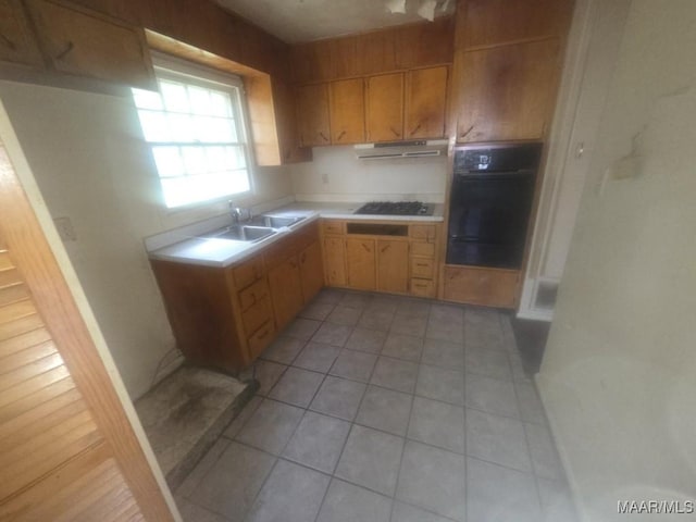 2930 Milton Rd, Montgomery, AL 36110 - kitchen featuring black oven, light countertops, under cabinet range hood, light tile patterned floors, and a sink
