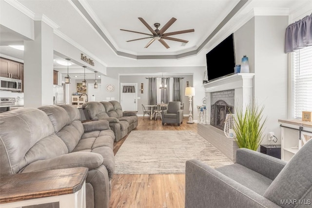 28 Lake Region Dr, Wetumpka, AL 36092 - living room with a ceiling fan, light wood-style flooring, a tray ceiling, a brick fireplace, and crown molding
