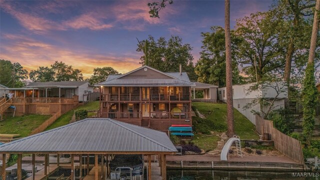 28 Lake Region Dr, Wetumpka, AL 36092 - back of house at dusk with metal roof, stairway, boat lift, and a balcony