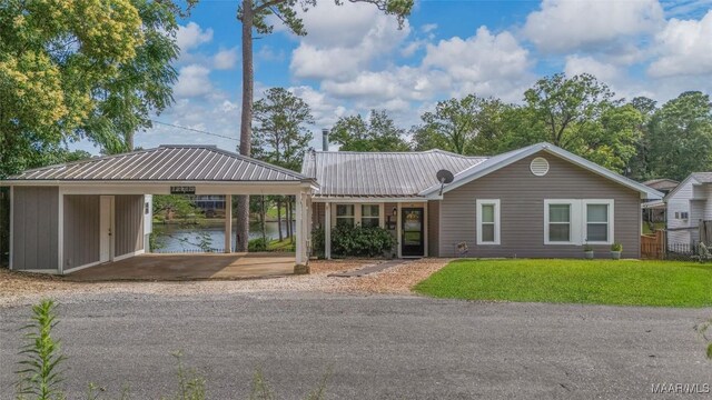 28 Lake Region Dr, Wetumpka, AL 36092 - ranch-style house featuring a front lawn, a carport, metal roof, driveway, and a water view