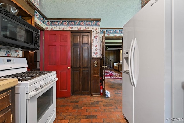 76 Willow Springs Rd, Wetumpka, AL 36093 - kitchen with white appliances, wallpapered walls, wainscoting, brick patterned flooring, and a textured ceiling