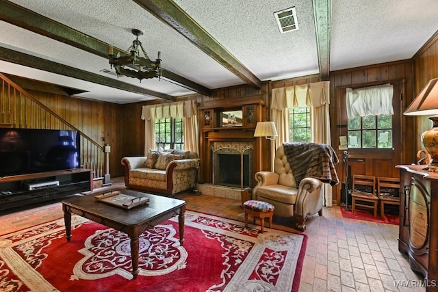 76 Willow Springs Rd, Wetumpka, AL 36093 - living area with wood walls, a textured ceiling, a chandelier, brick flooring, and a fireplace with raised hearth