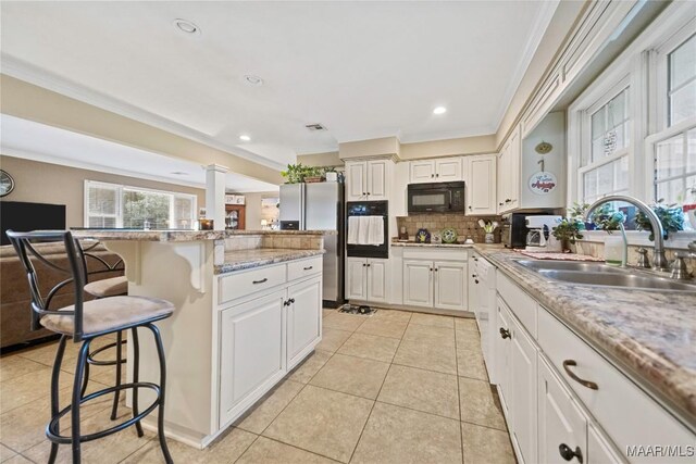 901 Green Forest Dr, Montgomery, AL 36109 - kitchen featuring black appliances, a kitchen breakfast bar, white cabinets, backsplash, and open floor plan