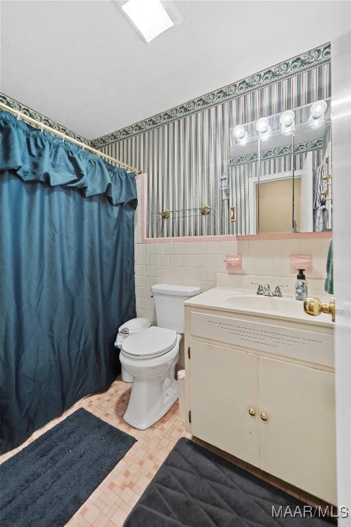 901 Green Forest Dr, Montgomery, AL 36109 - full bath with wallpapered walls, vanity, tile walls, a wainscoted wall, and a shower with shower curtain
