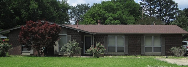 single story home featuring brick siding, a front yard, and a shingled roof
