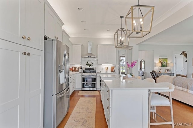 493 Lake Ridge Rd, Hope Hull, AL 36043 - kitchen featuring appliances with stainless steel finishes, wall chimney range hood, open floor plan, ornamental molding, and a chandelier