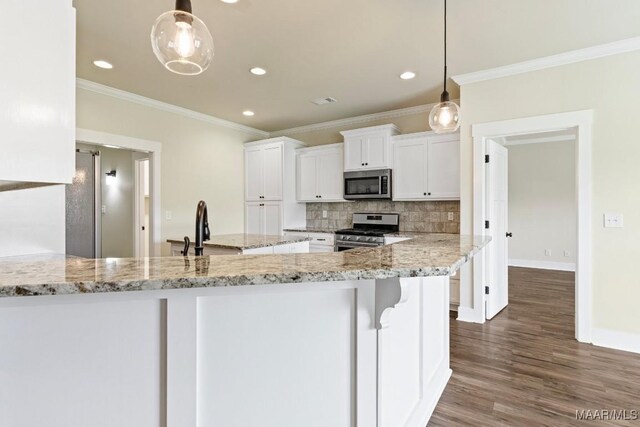 12 Crescent Ridge Ct, Deatsville, AL 36022 - kitchen featuring appliances with stainless steel finishes, decorative backsplash, white cabinetry, ornamental molding, and wood finished floors