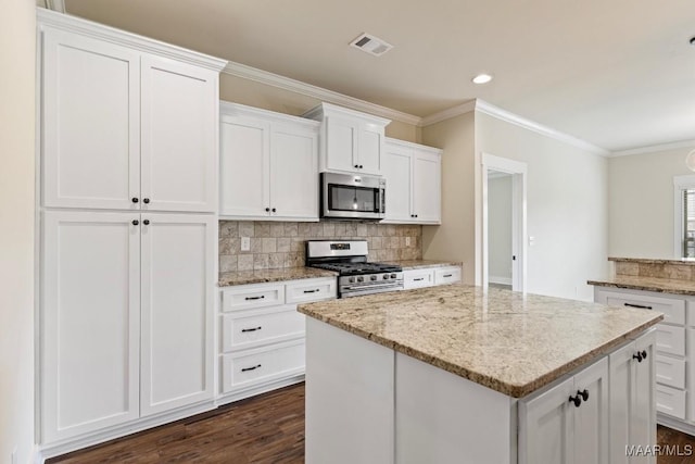 12 Crescent Ridge Ct, Deatsville, AL 36022 - kitchen featuring stainless steel appliances, backsplash, a kitchen island, white cabinets, and ornamental molding