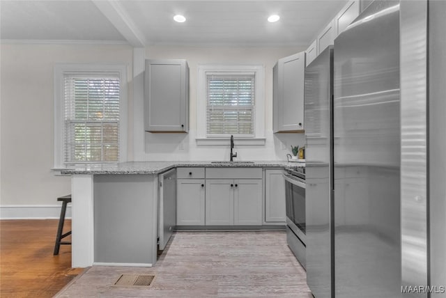 844 E Edgemont Ave, Montgomery, AL 36111 - kitchen featuring stainless steel appliances, a peninsula, light wood-style floors, light stone countertops, and a kitchen breakfast bar