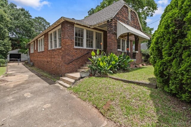 102 Vonora Ave, Montgomery, AL 36107 - view of home's exterior with brick siding, a yard, an outdoor structure, and roof with shingles