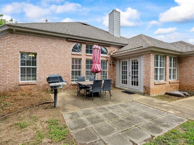 7117 Stamford Ct, Montgomery, AL 36117 - back of property with french doors, brick siding, a patio area, a chimney, and a shingled roof