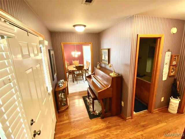5240 Airport Rd, Millbrook, AL 36054 - hallway featuring wallpapered walls, wood finished floors, and a chandelier