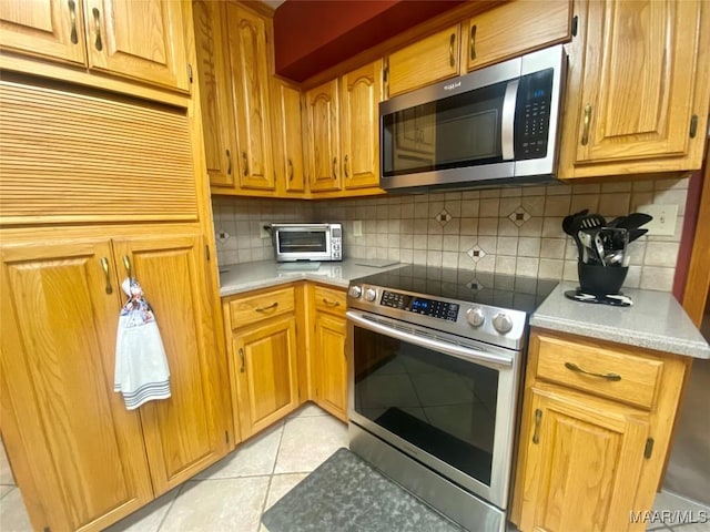 5240 Airport Rd, Millbrook, AL 36054 - kitchen with appliances with stainless steel finishes, light tile patterned floors, tasteful backsplash, light countertops, and brown cabinets