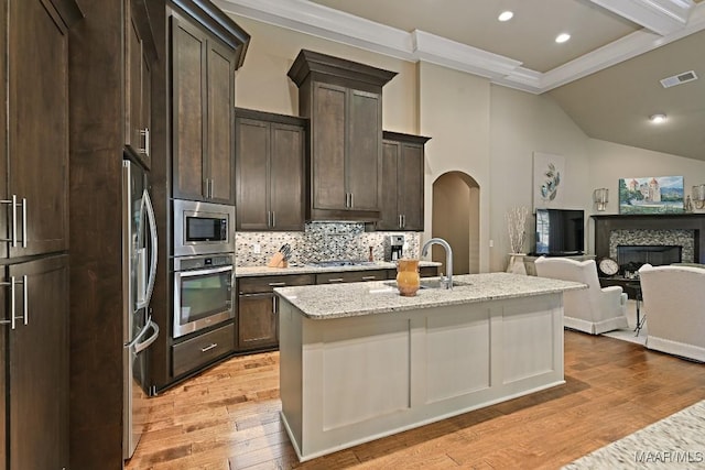 8612 Birchwood Ct, Montgomery, AL 36116 - kitchen featuring stainless steel appliances, arched walkways, open floor plan, decorative backsplash, and light wood finished floors