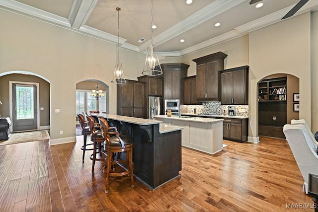 8612 Birchwood Ct, Montgomery, AL 36116 - kitchen featuring a kitchen island with sink, appliances with stainless steel finishes, arched walkways, dark brown cabinetry, and a chandelier