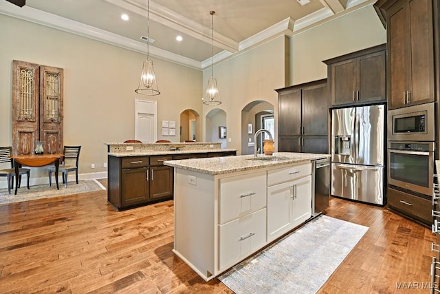 8612 Birchwood Ct, Montgomery, AL 36116 - kitchen featuring appliances with stainless steel finishes, an island with sink, arched walkways, ornamental molding, and dark brown cabinets