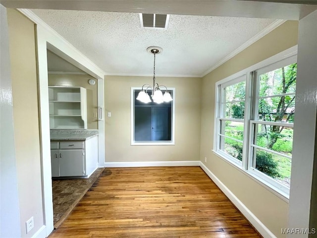 2441 Spruce Curv, Montgomery, AL 36107 - unfurnished dining area featuring a chandelier, wood finished floors, a textured ceiling, and crown molding