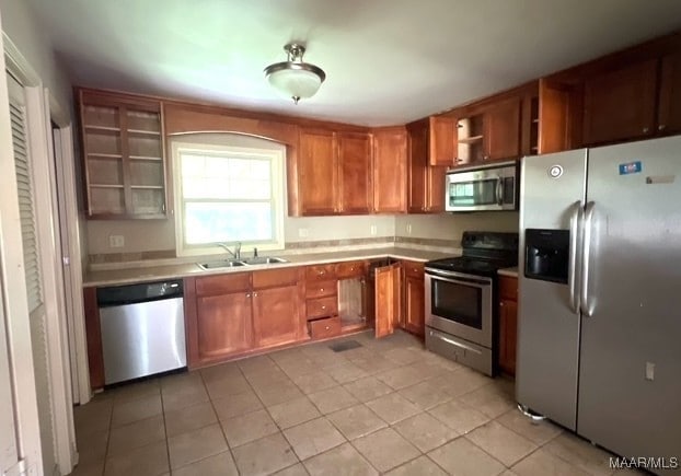 323 E Highland St, Dadeville, AL 36853 - kitchen featuring stainless steel appliances, open shelves, light countertops, brown cabinetry, and light tile patterned floors