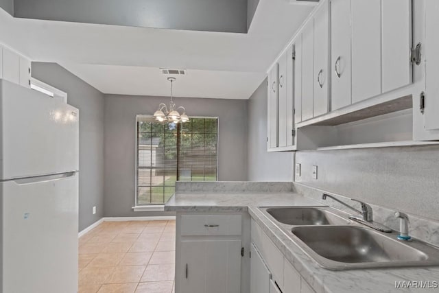 508 Ridgewood Ln, Montgomery, AL 36109 - kitchen with freestanding refrigerator, light countertops, a chandelier, light tile patterned floors, and white cabinetry
