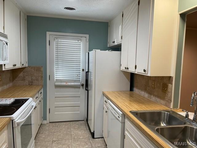 4447 Wares Ferry Rd, Montgomery, AL 36109 - kitchen with white appliances, white cabinetry, tasteful backsplash, light tile patterned floors, and light countertops