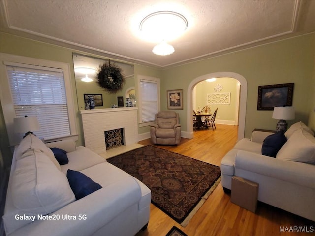 1928 Winona Ave, Montgomery, AL 36107 - living room featuring arched walkways, wood finished floors, a fireplace with flush hearth, and crown molding