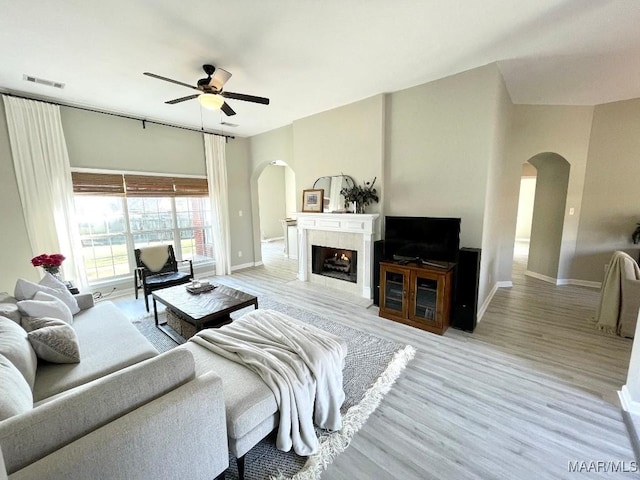 2495 Chancellor Ridge Rd, Prattville, AL 36066 - living room featuring arched walkways, ceiling fan, light wood-style flooring, and a tiled fireplace