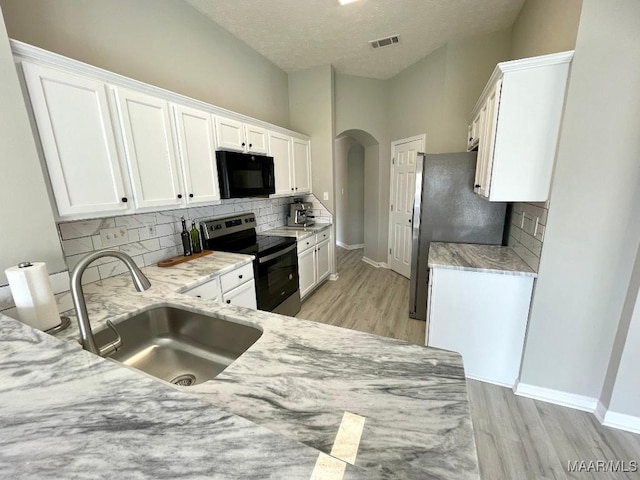 2495 Chancellor Ridge Rd, Prattville, AL 36066 - kitchen featuring appliances with stainless steel finishes, arched walkways, white cabinetry, light wood finished floors, and decorative backsplash