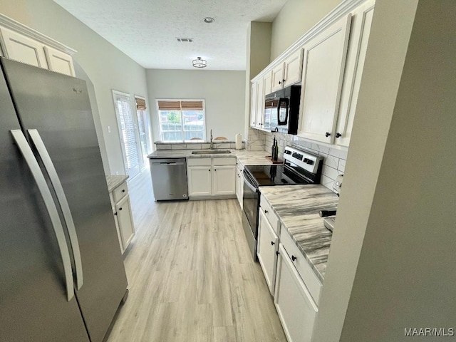 2495 Chancellor Ridge Rd, Prattville, AL 36066 - kitchen featuring stainless steel appliances, light wood-style floors, white cabinets, backsplash, and a textured ceiling