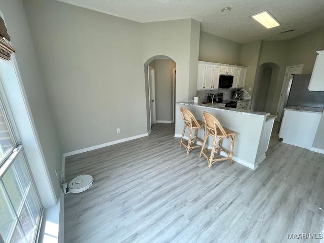 2495 Chancellor Ridge Rd, Prattville, AL 36066 - kitchen with black appliances, arched walkways, white cabinetry, and light wood finished floors