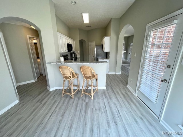 2495 Chancellor Ridge Rd, Prattville, AL 36066 - kitchen featuring freestanding refrigerator, white cabinetry, light wood-type flooring, a peninsula, and a textured ceiling