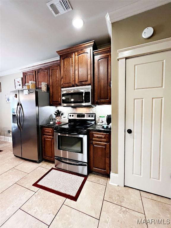 309 Southern Hills Dr, Wetumpka, AL 36093 - kitchen featuring appliances with stainless steel finishes, dark countertops, crown molding, light tile patterned floors, and dark brown cabinetry