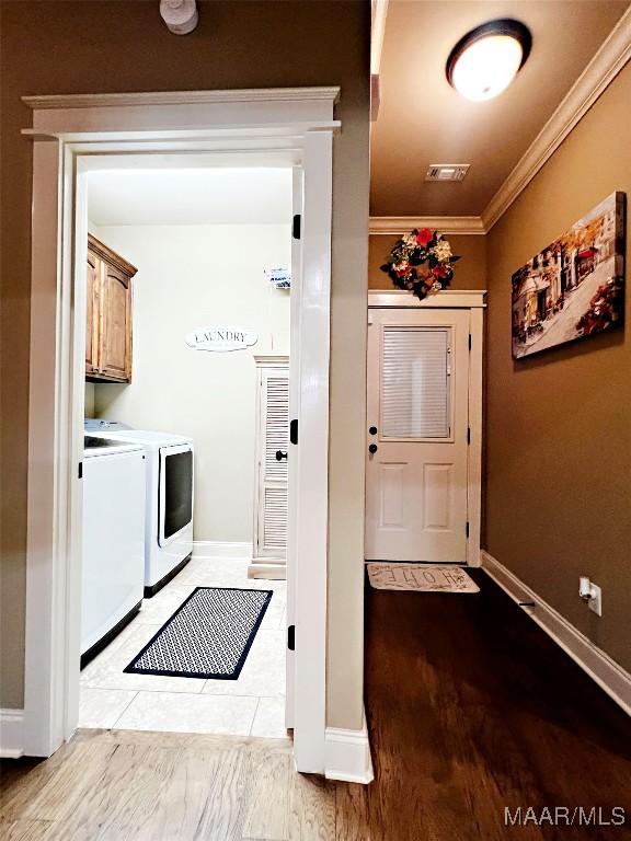 309 Southern Hills Dr, Wetumpka, AL 36093 - washroom with washer and clothes dryer, cabinet space, ornamental molding, and light wood-type flooring