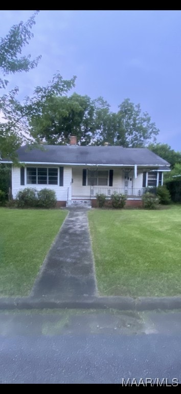 407 Powers Ave, Tallassee, AL 36078 - view of front of house with a porch, a front yard, and a chimney