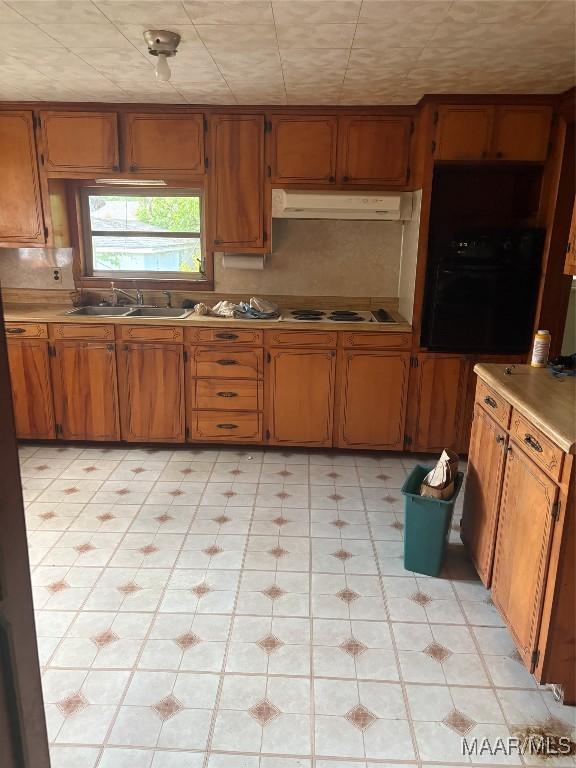 407 Powers Ave, Tallassee, AL 36078 - kitchen featuring oven, under cabinet range hood, brown cabinets, and light countertops