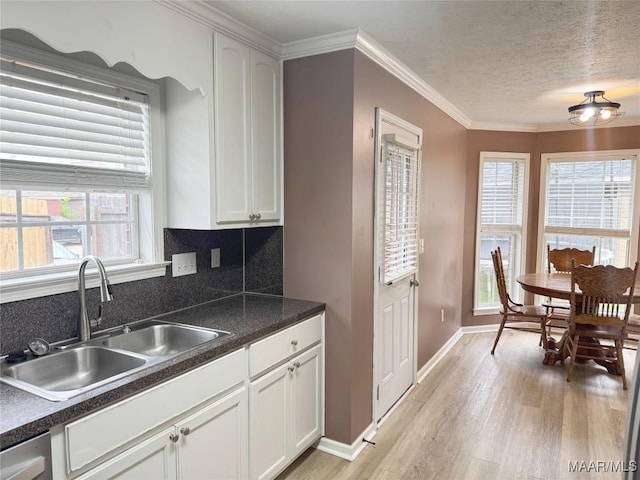 1312 Centerfield Ct, Montgomery, AL 36117 - kitchen featuring light wood-type flooring, dark countertops, white cabinets, ornamental molding, and decorative backsplash