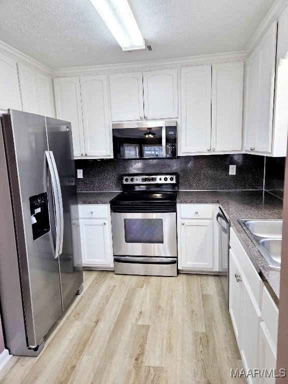 1312 Centerfield Ct, Montgomery, AL 36117 - kitchen featuring stainless steel appliances, white cabinetry, light wood-style floors, and a textured ceiling