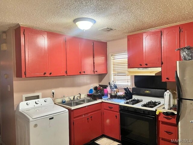 530 Brookview Dr, Montgomery, AL 36110 - kitchen with washer / dryer, under cabinet range hood, freestanding refrigerator, range with gas cooktop, and red cabinetry