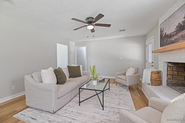 5010 Redland Rd, Wetumpka, AL 36093 - living room featuring light wood-style floors, a ceiling fan, a brick fireplace, and a textured ceiling