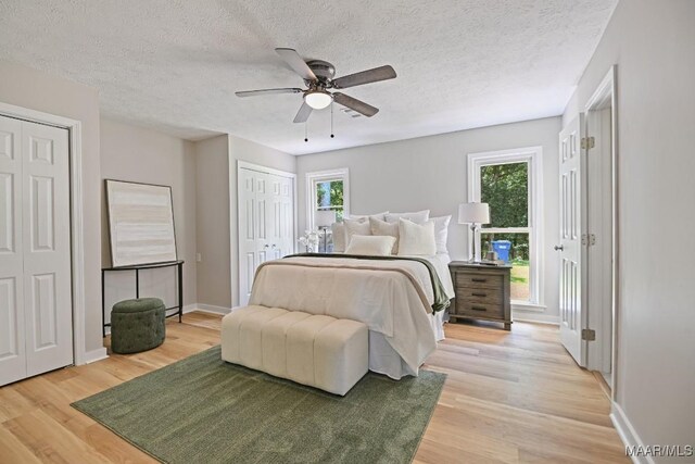 5010 Redland Rd, Wetumpka, AL 36093 - bedroom featuring two closets, light wood-style flooring, a textured ceiling, and a ceiling fan