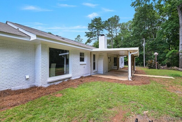 5010 Redland Rd, Wetumpka, AL 36093 - rear view of property featuring brick siding, a chimney, a lawn, and a patio