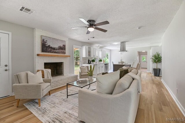 5010 Redland Rd, Wetumpka, AL 36093 - living room featuring light wood-style flooring, a textured ceiling, ceiling fan, and a brick fireplace