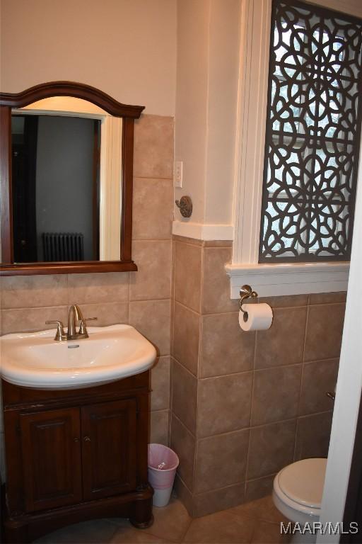 2207 Winona Ave, Montgomery, AL 36107 - bathroom featuring tile walls, vanity, radiator heating unit, and tile patterned flooring